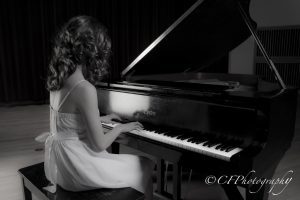 Girl sitting at the piano playing.