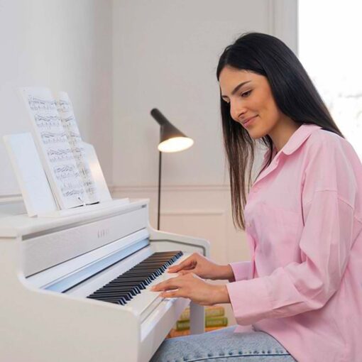 Image of woman in pink shirt, shown from the side, sitting at a white Kawai CA501