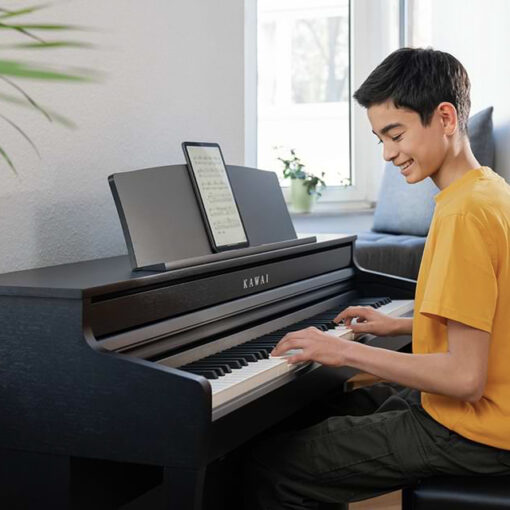 Image of young boy playing a Kawai CA401 digital piano with an iPad on the music stand.