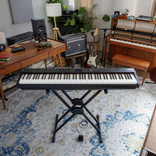 Image showing a Roland RD-08 set up on a KS-20X Roland Stand, in a musical living room with piano and amp in the background.