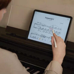 Image of a woman using Casio Music Space app on a tablet, seated in front of an AP-S450 digital piano