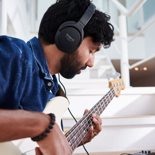 Picture of man wearing RH-5 Headphones while playing electric bass.