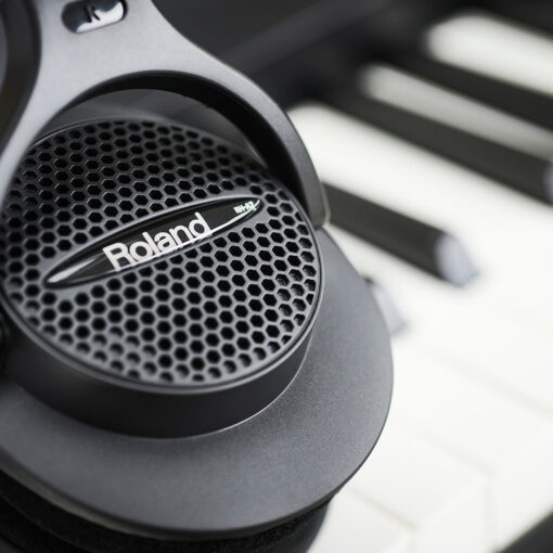 Close-up image of a pair of Roland RH-A7 headphones sitting on a piano keyboard.