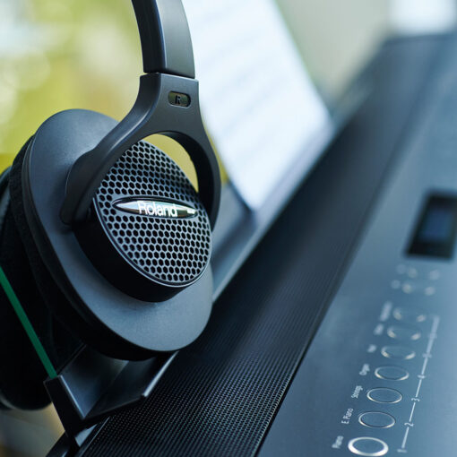 Side shot of Roland RH-A7 headphones sitting on a Roland FP-90x digital piano.