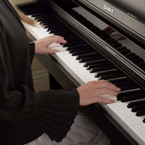 A piano player holds their hands on the keys of a Casio AP750bk